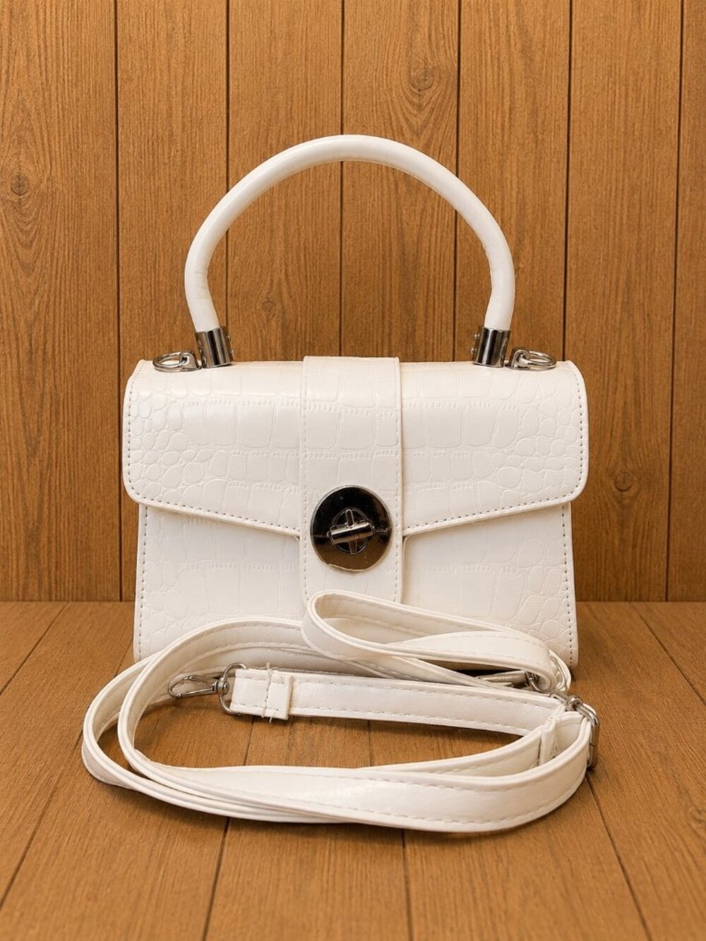 White crocodile-textured structured handbag featuring a flap opening